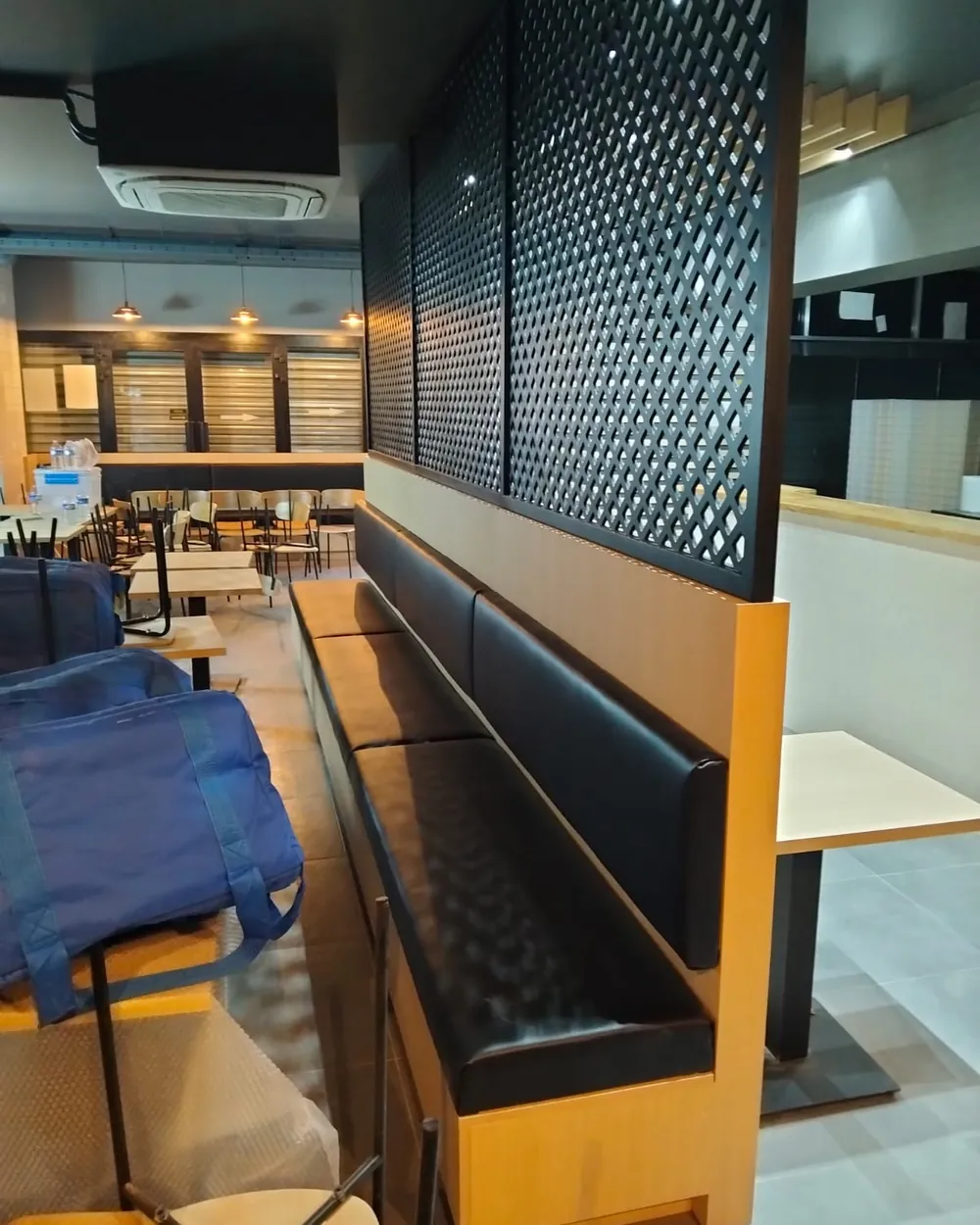 Banquettes de restaurant en cuir noir et claustra bois